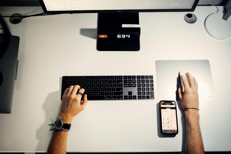 a person's feet on a white table with a computer and a keyboard